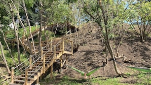 Un escalier en bois menant à une plateforme sur laquelle est installé un hamac.