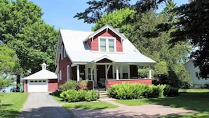 Une maison rouge avec un porche blanc et un garage.