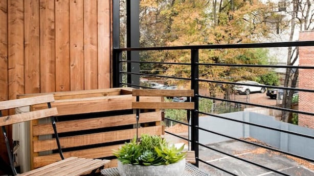 A balcony with a wooden bench and a small table with a potted plant.