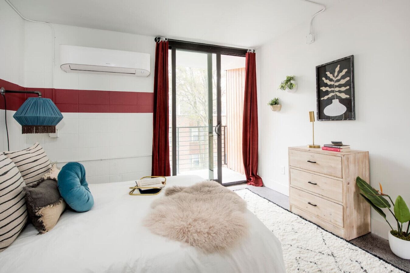 Une chambre à coucher moderne avec un lit, une commode, une fenêtre avec des rideaux et une plante en pot.