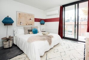 Relax in this serene bedroom with a large bed, abstract art, and a sliding door to an outdoor area.