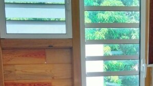 A compact kitchen with wooden cabinetry, a microwave, a small refrigerator, a water dispenser, and a window with blinds. - Studio Lumineux Dans Quartier Calme, Avec Terrasse, 5 mn à Pied du Centre Ville (Basse-Terre)