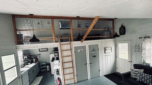 Una habitación compacta, de varios niveles, con zona superior, cocina y un pequeño espacio para sentarse.