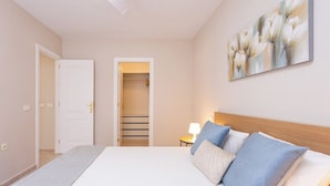 A bedroom with a bed, pillows, a nightstand, a lamp, and a painting on the wall. - Home2Book Attic Terrace Apt Charming Ocean View (Las Caletillas)