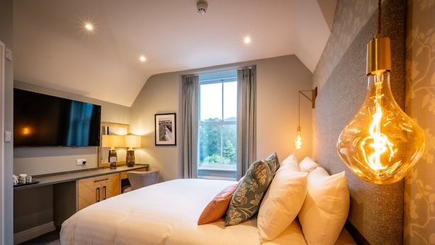 A modern hotel room with a large bed, a desk, a flat-screen TV, and a unique light fixture. - Ambleside Fell Rooms (Ambleside)