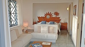 Una habitación de hotel con una cama, un sofá, una mesita de café y una mesita de noche.