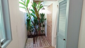 Un pasillo estrecho con pared de azulejos, suelo de madera y una puerta con listones horizontales.
