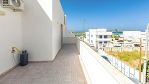 Ein Balkon mit Warmwasserbereiter, Gasflasche und Blick auf das Meer und Gebäude.