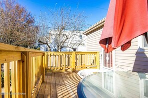 Relax on the deck with a hot tub or pool, surrounded by a wooden railing and leafless trees.
