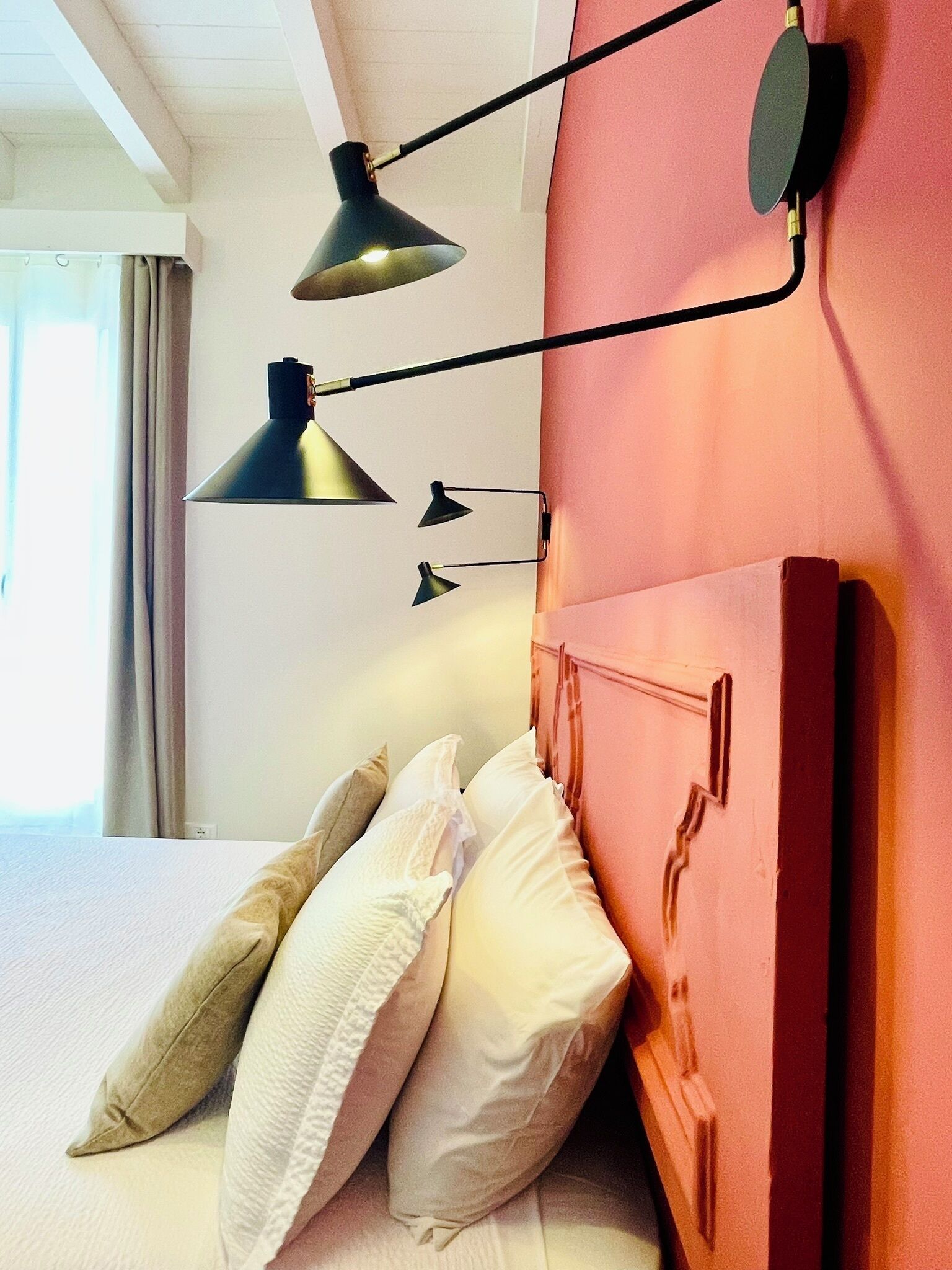 A hotel room with a bed, pillows, and a headboard.