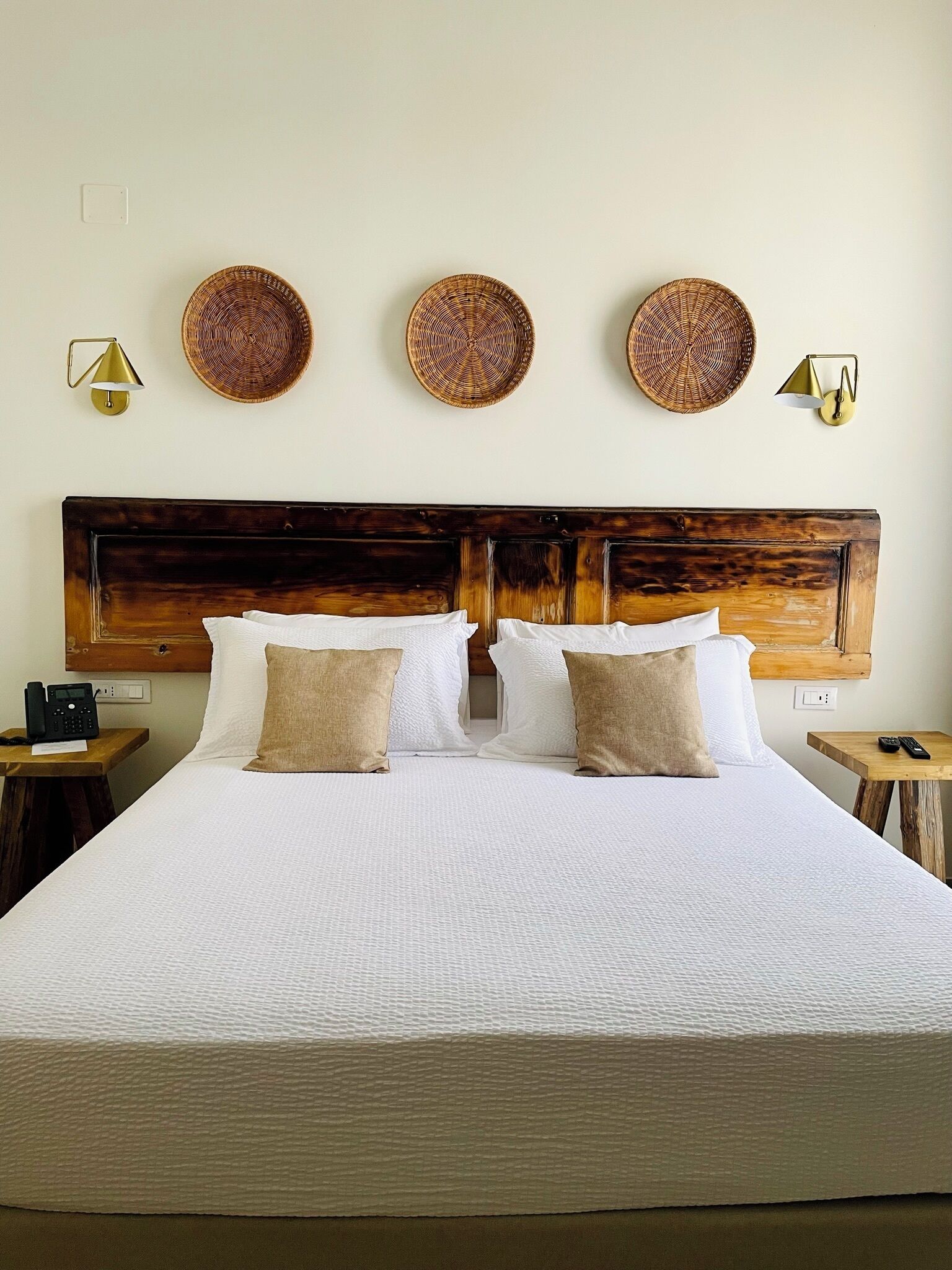 A large bed with a wooden headboard, white bedding, and two bedside tables with lamps.