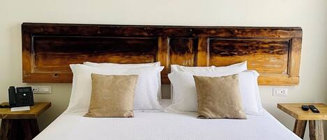 A large bed with a wooden headboard, white bedding, and two bedside tables with lamps.