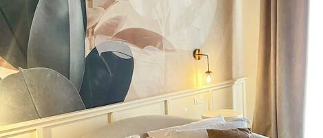Un dormitorio con una cama grande, una lámpara de pared y un cuadro abstracto de gran tamaño.