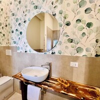 Un baño con un espejo redondo, un lavamanos blanco y un mueble de tocador de madera.