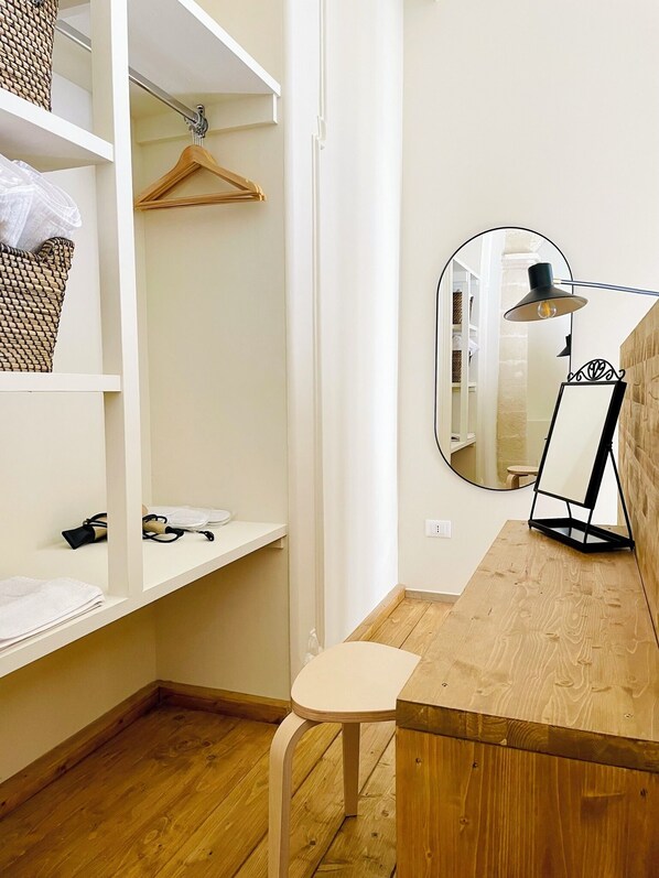 A small, neatly organized room with a wooden desk, a mirror, and a hanging clothes rack. - Palazzo Matà Boutique Hotel (Taranto)