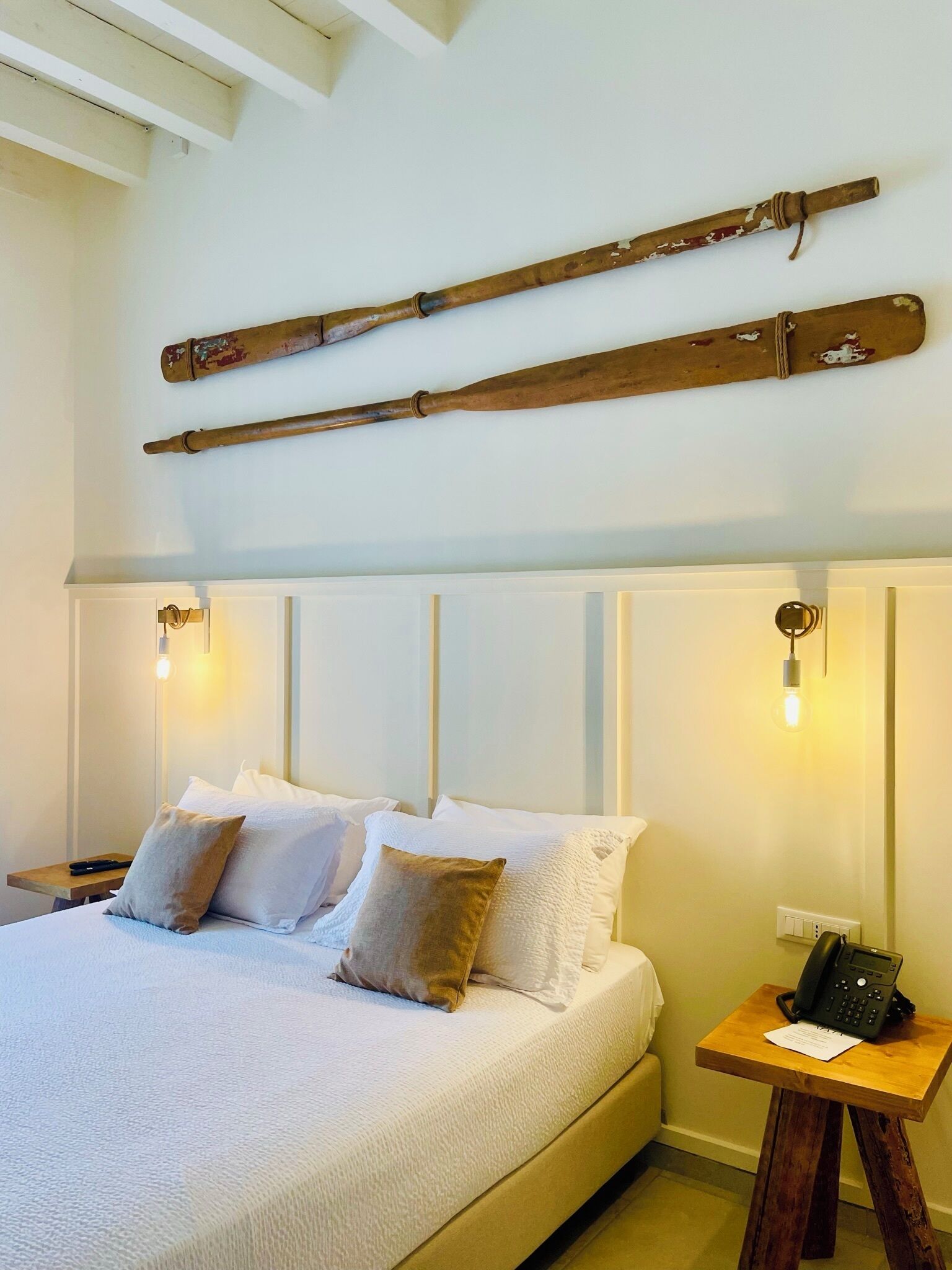 Ein Schlafzimmer mit einem Bett, Kissen, einem Nachttisch mit Telefon und Holzbalken an der Wand.