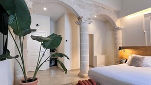 Une chambre moderne avec un grand lit, un coin salon avec un fauteuil et une plante en pot.