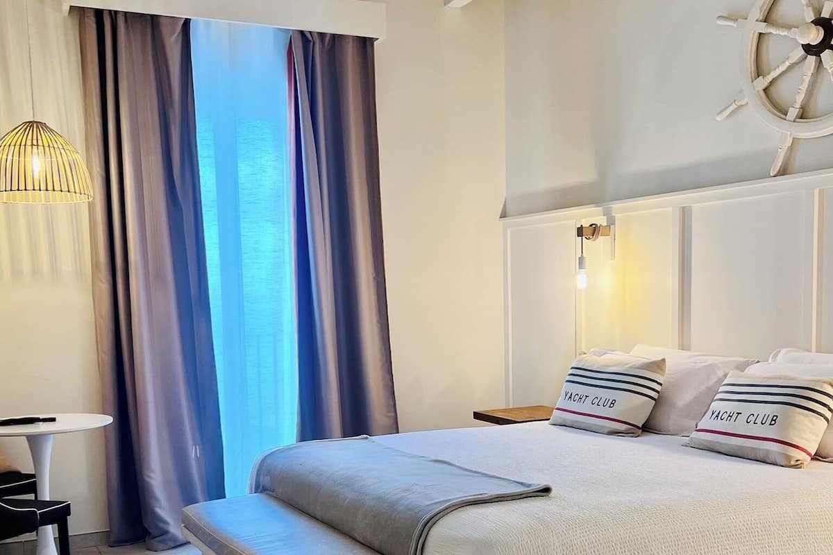 Une chambre à coucher avec un lit, un banc, une table et des rideaux.