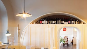 Un espace bar avec un présentoir à bouteilles de vin, un comptoir d’accueil et un coin salon comprenant des chaises et une table.
