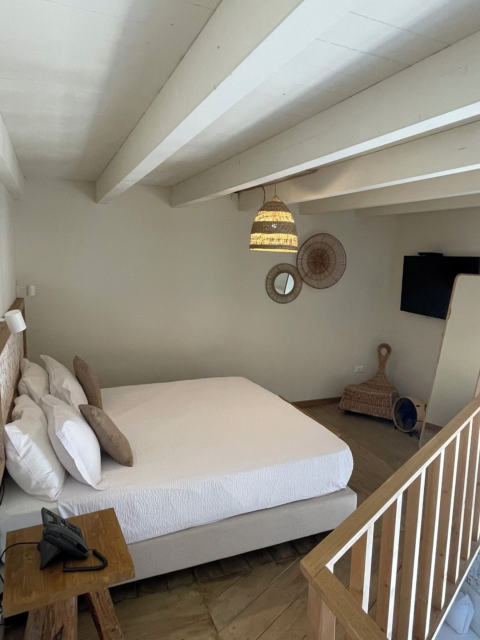 A bedroom with a bed, bedside table, and a hanging light fixture.