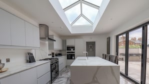A modern kitchen with white cabinetry, a central island, and a skylight. - Church View (Scarborough)