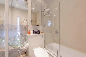 A modern bathroom with a glass-enclosed shower, a glass sink, and a white toilet. - Stylish 1BD Flat 5 Mins to Harrods- Knightsbridge (London)