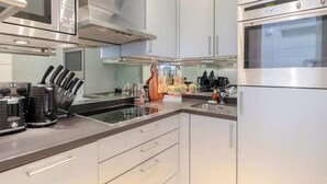 A modern kitchen with stainless steel appliances, a glass countertop, and a variety of utensils. - Stylish 1BD Flat 5 Mins to Harrods- Knightsbridge (London)