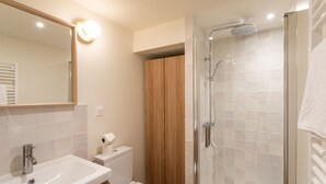 A modern bathroom with a sink, toilet, and glass-enclosed shower.