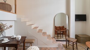 A modern interior with a staircase, dining area, and seating.