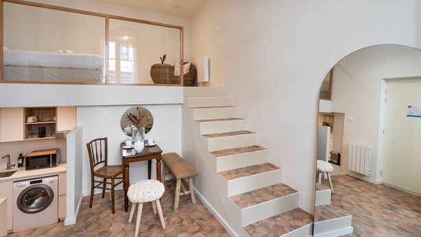 A compact living space with a kitchen, dining area, and a staircase.