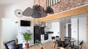 A modern living room with a black sofa, a round coffee table, and a dining area with a black table and chairs. - Le Saint Martin Bis - Bel appartement moderne et confortable (Rennes)