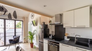 A modern kitchen with a black countertop, stainless steel appliances, and a large window offering a view of the city. - Le Saint Martin Bis - Bel appartement moderne et confortable (Rennes)