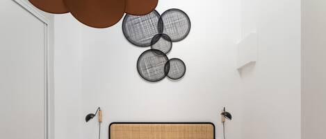 A neatly made bed with two decorative pillows, a headboard, and a wall-mounted light fixture.