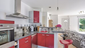 Cocina moderna con armarios rojos, electrodomésticos de acero inoxidable y una isla central con fregadero y taburetes de bar.
