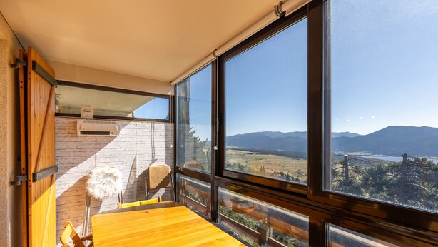 Ein Zimmer mit großem Fenster und Blick auf Berge und Fluss.
