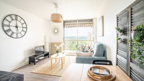 Ein modernes Wohnzimmer mit einer großen Wanduhr, einem Sofa, einem Couchtisch und einem Fernseher.