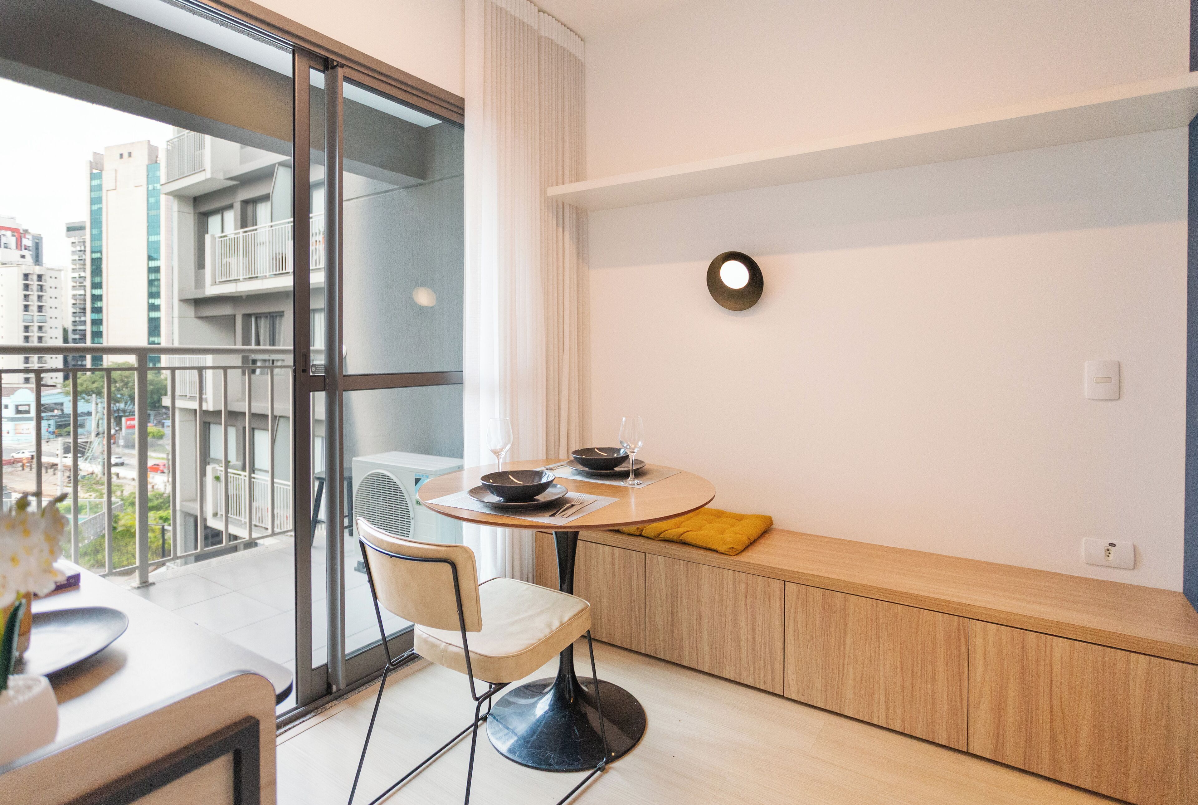 Un apartamento moderno con balcón, un comedor con mesa redonda y vistas a la ciudad.