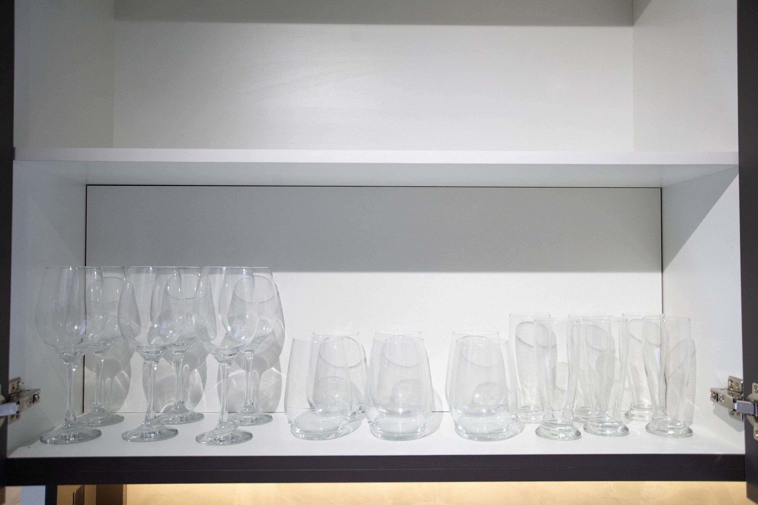 A shelf with multiple clear glass wine glasses.
