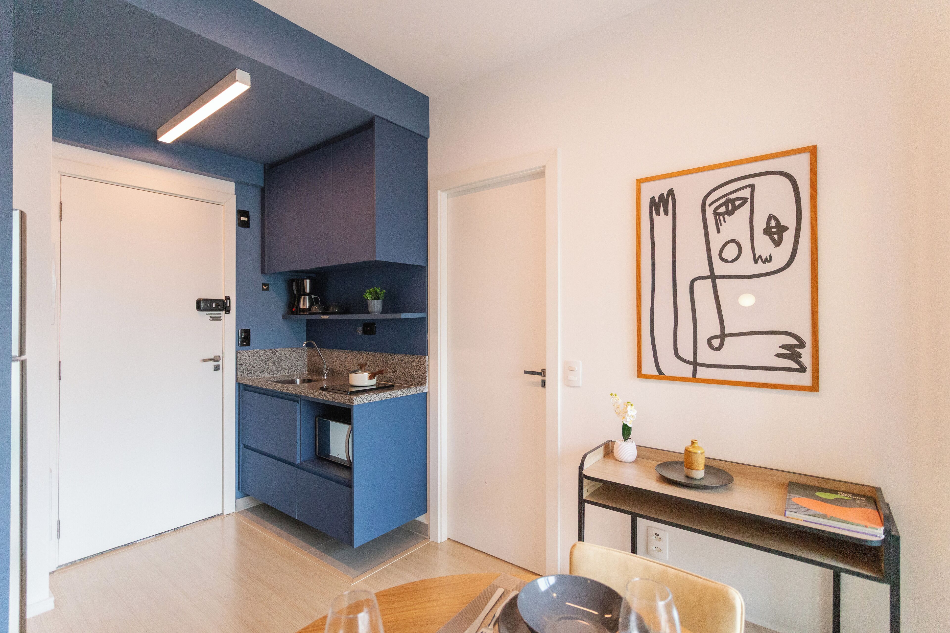 A modern kitchen with blue cabinets, a built-in oven, and a dining area with a table and chairs.