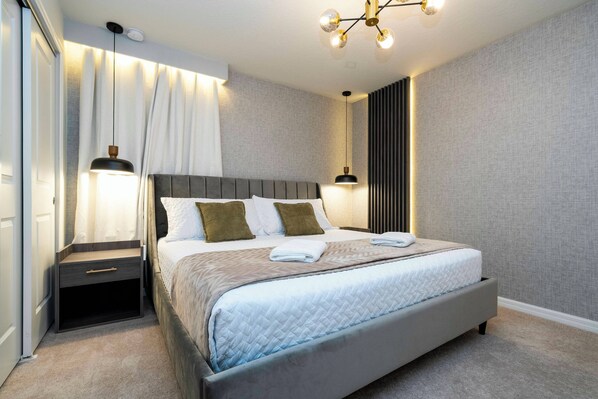 A modern bedroom with a large bed, bedside tables, and a ceiling light fixture. - Windsor Island 7BR - Pool, Spa & Fireworks View - Free Pool Heat + BBQ in Aug (Orlando)