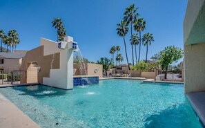 A swimming pool with a water feature, surrounded by palm trees and buildings. - Modern Loft Style Condo at Udall Park (Tucson)