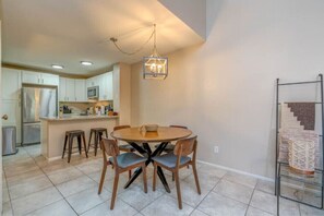 A modern kitchen with a central island, bar stools, and a hanging light fixture.