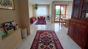 A spacious living area with a large rug, a wooden cabinet, and a television in the background. - Elegante alloggio di grandi dimensioni (110 mq) in parco privato di 6000 mq (Torino)