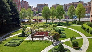 A landscaped courtyard with a central garden, surrounded by residential buildings and a parking area. - Elegante alloggio di grandi dimensioni (110 mq) in parco privato di 6000 mq (Torino)