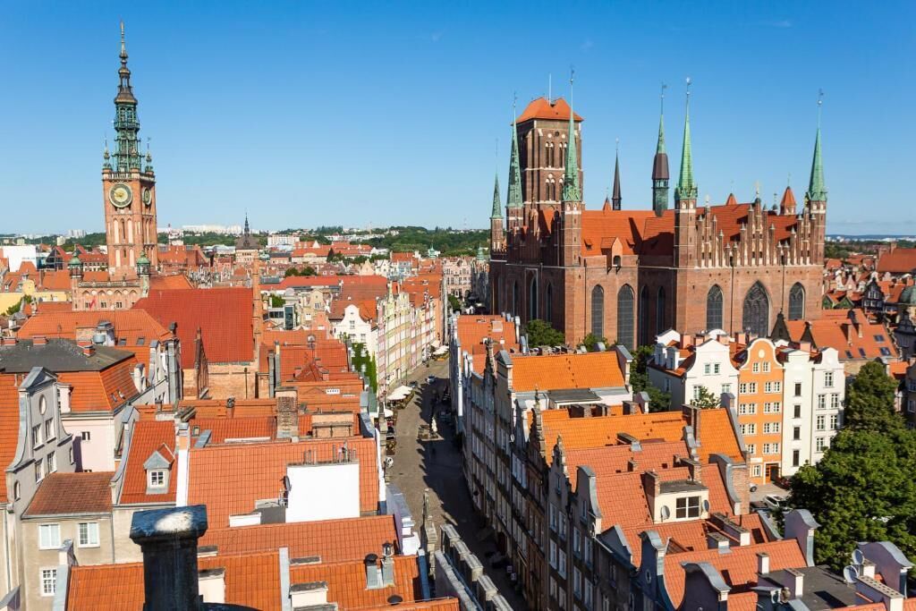 Stadsgezicht met historische gebouwen, een opvallende kerk met een hoge toren, en een klokkentoren.