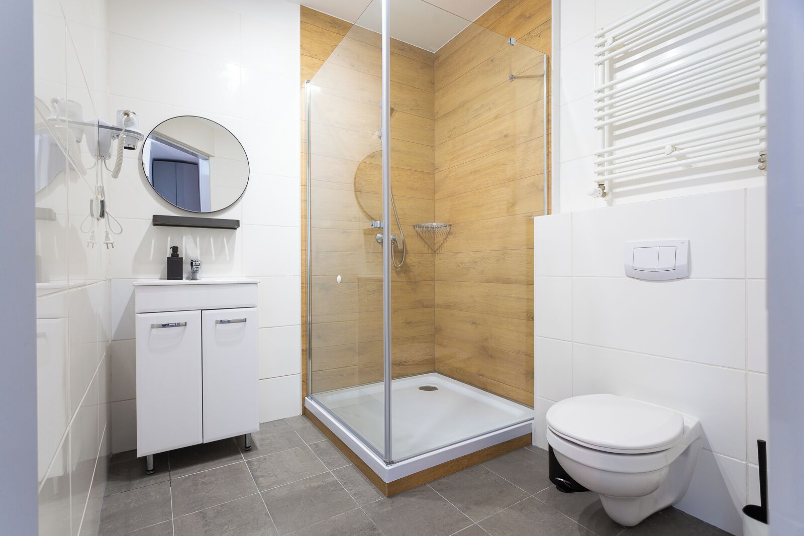 A modern bathroom with a glass-enclosed shower, a white toilet, and a vanity with a mirror.