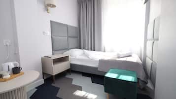 Een moderne hotelkamer met een bed, nachtkastje, lamp en uitzicht op het groen.
