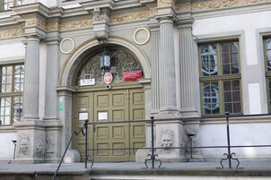 Egy nagyméretű, íves bejárattal, oszlopokkal és egy „Mon Apartments” feliratú táblával ellátott épület.