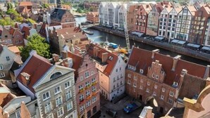 A high-angle view of a historic European town with narrow streets, traditional architecture, and a river. - Moon Apartments Gdańsk (Gdansk)