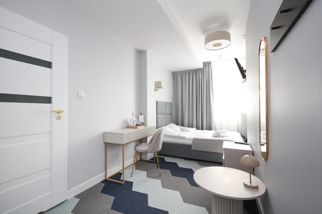 Ett modernt hotellrum med en säng, ett skrivbord, en stol och ett runt bord.
